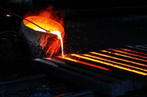 Hot molten metal being poured into long, thin cast.