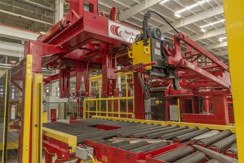 An impressive, fire-engine red piece of machinery known as a Red Bud Slitter housed in NMM’s brightly lit manufacturing facility, as part of their advanced high-strength steel slitting line.