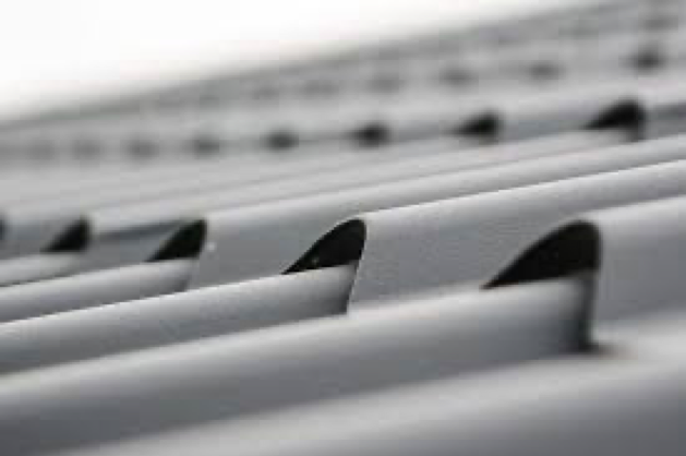 A view along a roofline of a galvanized steel surface that resembles the overlaid shingles of a building.