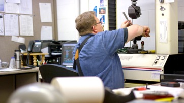 A metallurgist works diligently at a high tech workstation in National Material’s bright, well organized, in-house metallurgy lab.