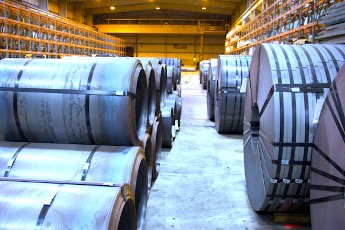 A warehouse with 2 rows of banded flat rolled steel stretching to the far back wall.