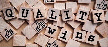 Little, square, wooden Scrabble-like tiles on a table, with the words “quality wins” spelled out and a few tiles with a hand giving a thumbs-up.